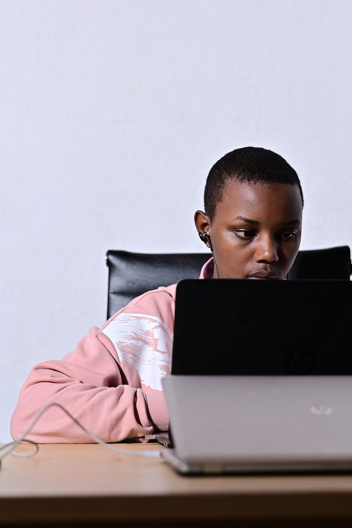 about-us-02 A young adult focused on work while using a laptop indoors. Ideal for remote work themes.