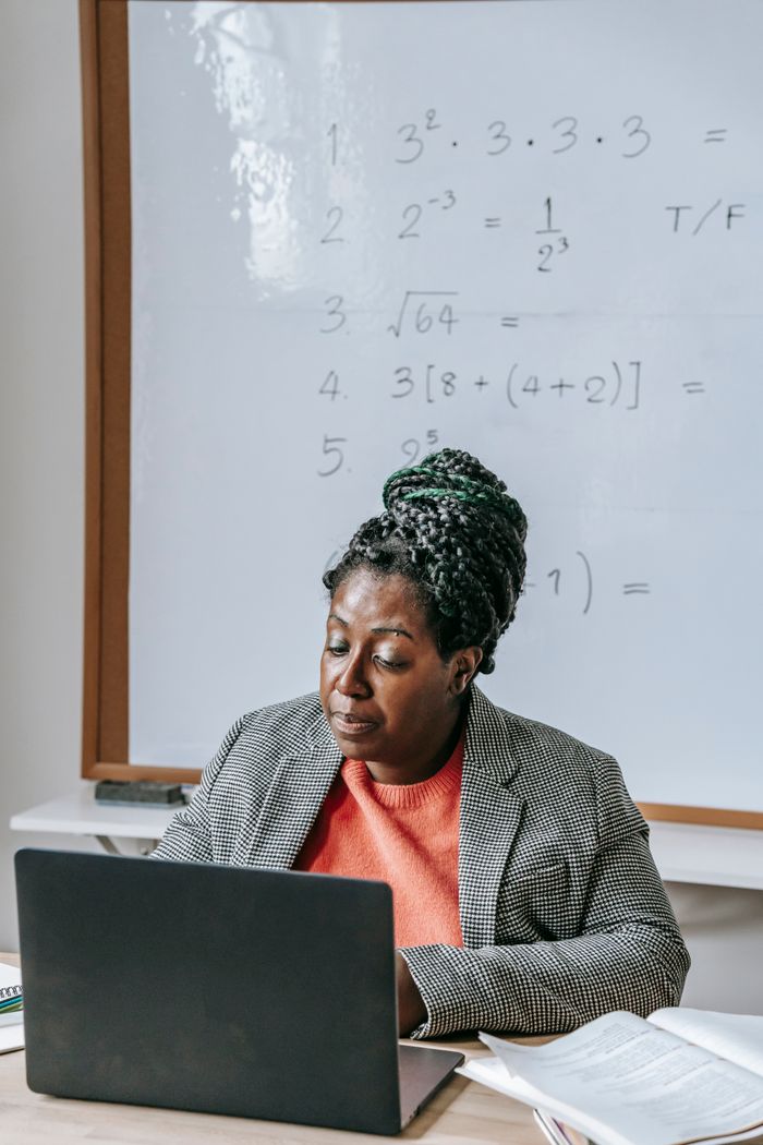 about-us-01 Intelligent African American female explaining difficult task online on netbook in classroom with whiteboard