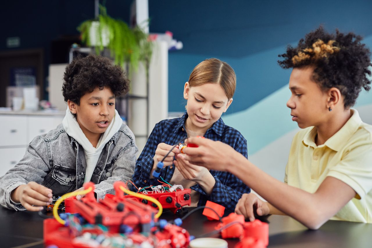 about-us-02 Diverse teens working together on a robotics project, showcasing teamwork and learning.